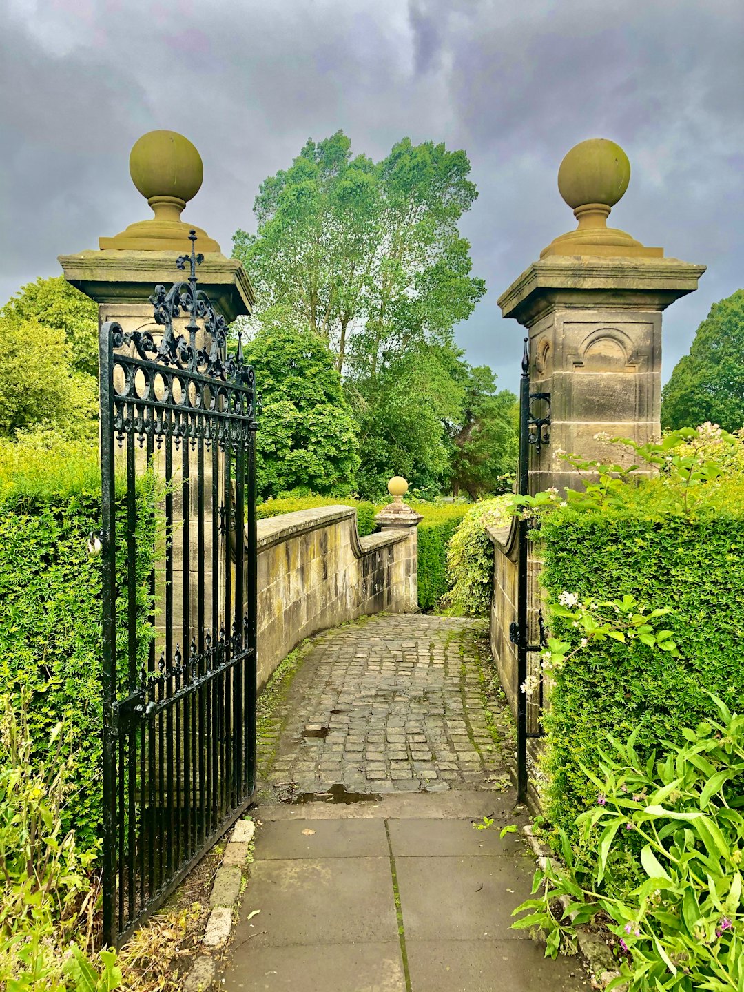 Ornate wrought iron gate leading to a lush green garden.